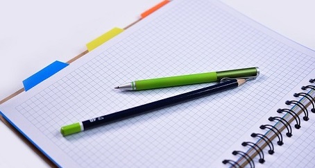 Geöffnetes Notebook mit leeren Seiten und zwei Stiften
